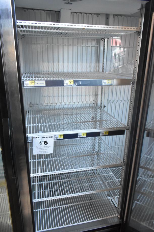 True GDM-72F-HC 3 Door Reach-In Freezer, commercial, 115V, shelves visible, price tags on racks, clean condition.