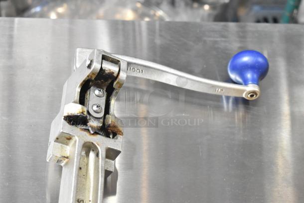 Edlund commercial can opener with blue handle, mounted on a metal surface, showing signs of wear and rust.