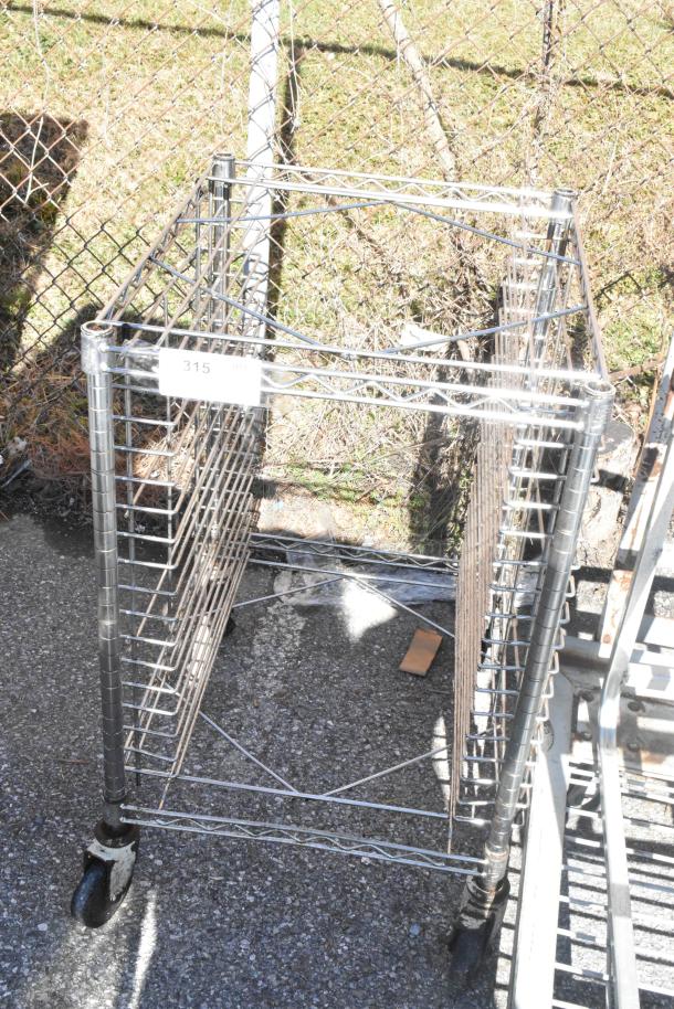Chrome finish pan transport rack with commercial casters, multiple shelf slots, outdoor setting, tag labeled "315."