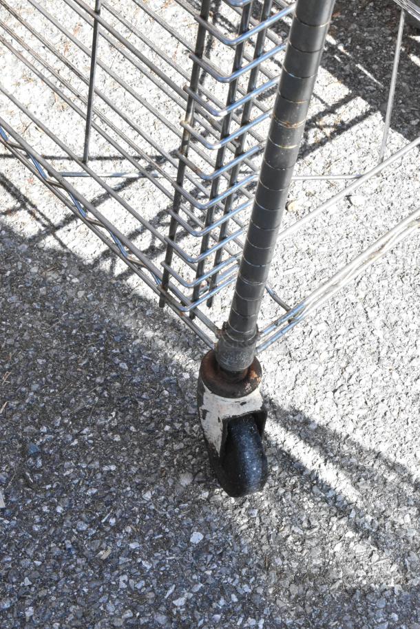 Chrome finish pan transport rack with sturdy wire shelves on commercial casters, slight rust on wheel area.