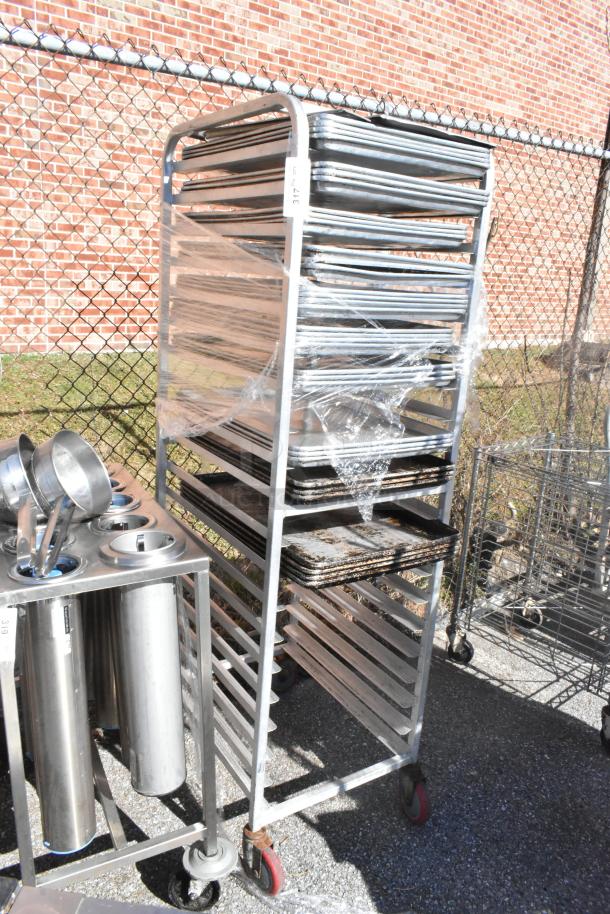 Commercial pan transport rack on casters with 30 baking pans, used condition, wrapped in plastic, metal frame.
