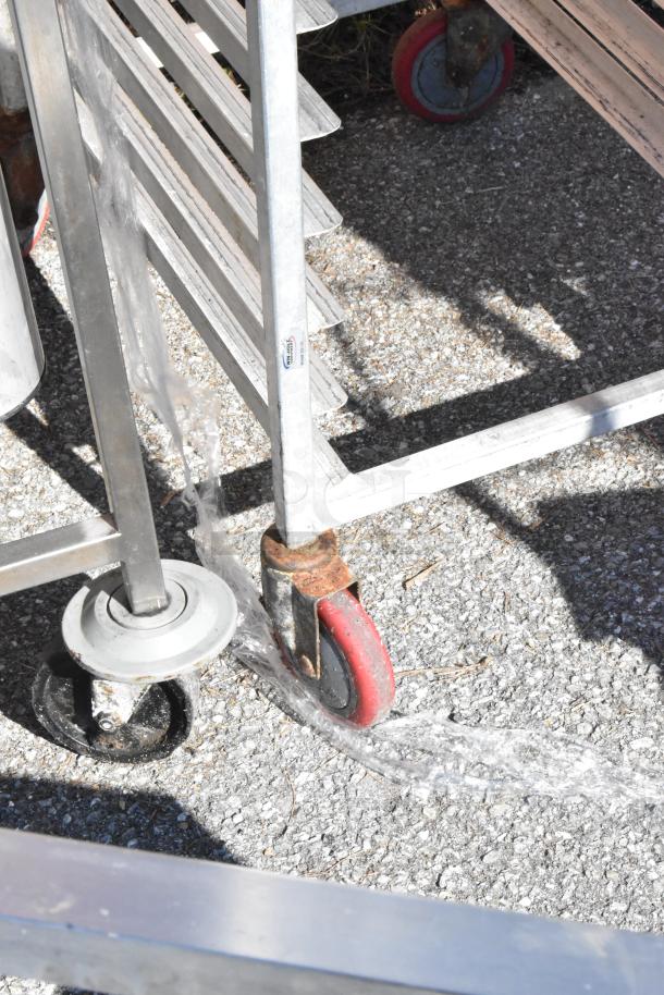 Commercial pan transport rack with 30 baking pans on metal casters, moderate wear, featuring a visible manufacturer's label.
