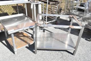 Two metal equipment stands, one with a lower rusted shelf, both in weathered condition, placed outdoors.