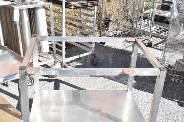 Two metal equipment stands with sturdy frames and flat surfaces, suitable for industrial use. Visible wear and outdoor condition.