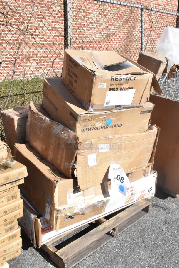 Stack of six new scratch and dent items, including Regency dishwasher stand, in original packaging on a pallet.