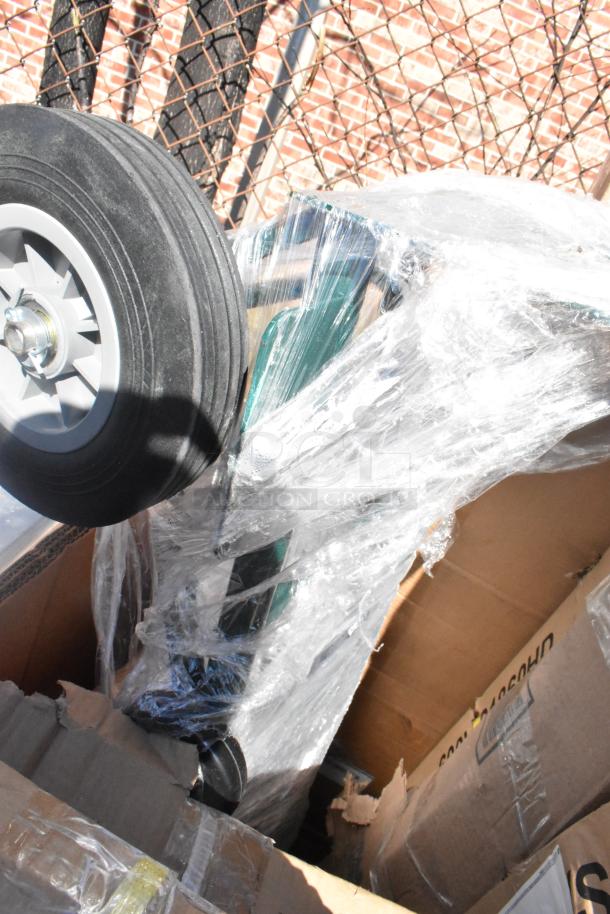 Nine brand new scratch and dent items in packaging, including shelves and table bases. Visible wheel and boxes, wrapped in plastic.
