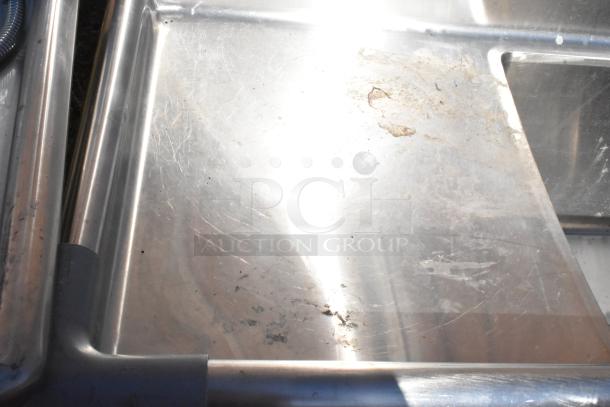 Commercial 3 bay sink with dual drain boards, stainless steel, lightly scratched surface, some residue visible.