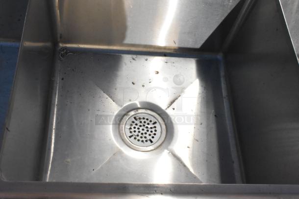 Commercial 3 bay stainless steel sink with drain, featuring dual drain boards. Slightly worn condition, ideal for kitchen use.