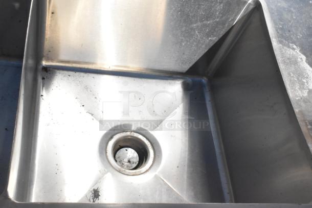 Commercial 3 Bay Sink with dual drain boards, stainless steel, some wear visible around drain, suitable for heavy-duty use.