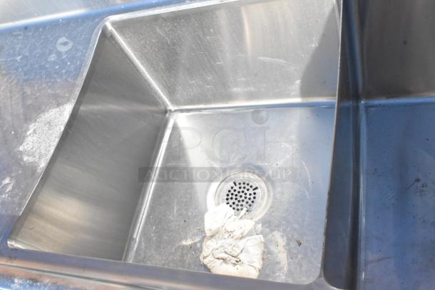 Commercial stainless steel 3 bay sink with dual drain boards. Durable, slightly used condition with minor surface marks.