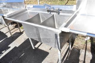 Commercial 2-bay stainless steel sink with left side drain boards, faucet, sturdy build, used condition.