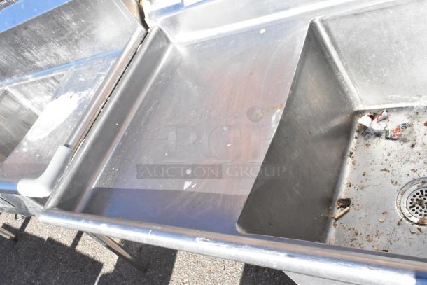 Commercial 2 bay sink with left side drain boards, stainless steel, visible wear and grime, includes drain and piping.