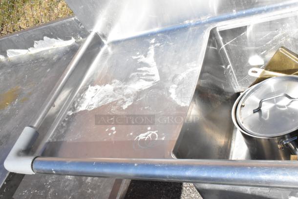 Commercial 3 bay sink with dual drain boards, stainless steel, used condition, with visible surface stains and scratches.