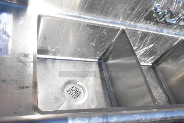 Commercial 3 Bay Sink with dual drain boards, stainless steel, visible signs of use, with faucet and drain details.
