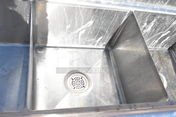 Commercial 3 bay stainless steel sink with dual drain boards, showing moderate use, featuring individual drains.