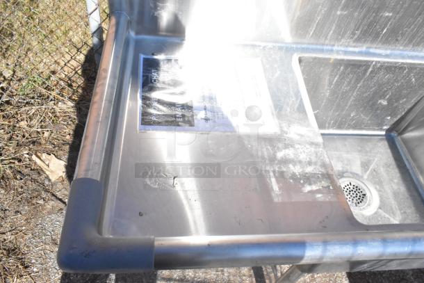 Commercial 3 bay stainless steel sink with dual drain boards, visible wear, and drainage features; ideal for restaurant use.