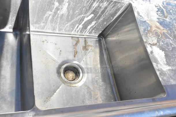Commercial 3 bay sink with dual drain boards, stainless steel, shows signs of use and wear, ideal for restaurant kitchens.
