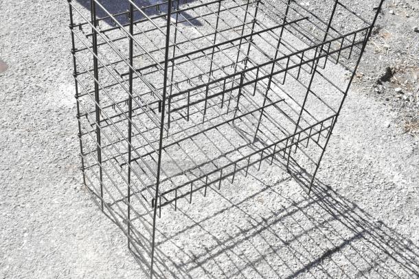 Black metal merchandising rack with multiple shelves, outdoor setting. Needs dismantling for transport. Cash register included.