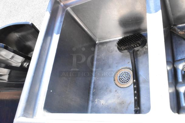 Commercial 3 bay sink with left side drain board, stainless steel, includes cleaning brush inside one bay, used condition.