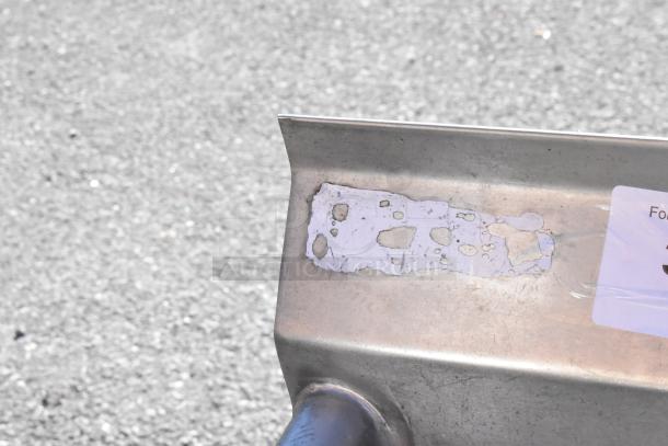 Commercial 3 bay sink corner detail showing metal surface with visible wear and old adhesive residue. Left side drain board.