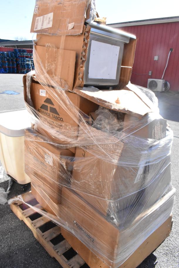 A pallet with 7 brand new scratch and dent items, including sinks, in partially damaged boxes wrapped in plastic. Labels indicate Advance Tabco.