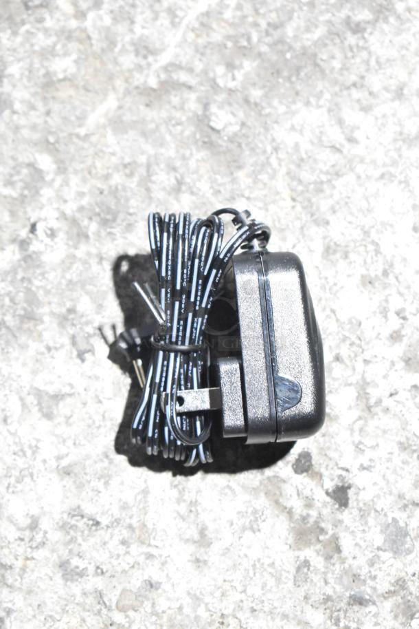 Bundle of hardware including Flojet 20578007C with power cords, wrapped and coiled neatly on a stone surface.