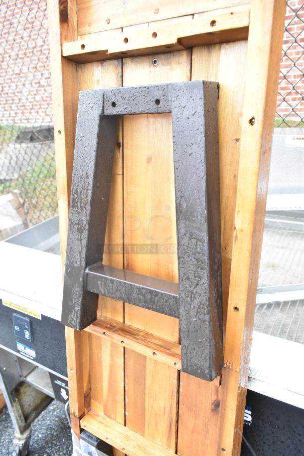 Wooden butcher block tabletop with attached black legs, showcasing natural wood texture. Slightly weathered condition.