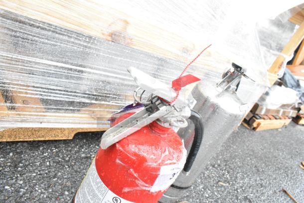 Pair of fire extinguishers, one red and one chrome, on pallet. Auction item, local pickup required.
