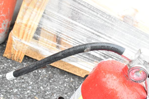 Two red fire extinguishers, visible hose, damp surface, must pick up, no shipping available.