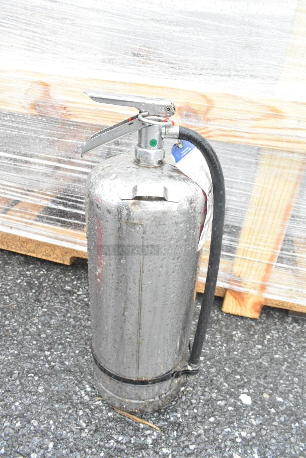 Stainless steel fire extinguisher with attached hose, labeled and slightly worn, available for local pickup only.