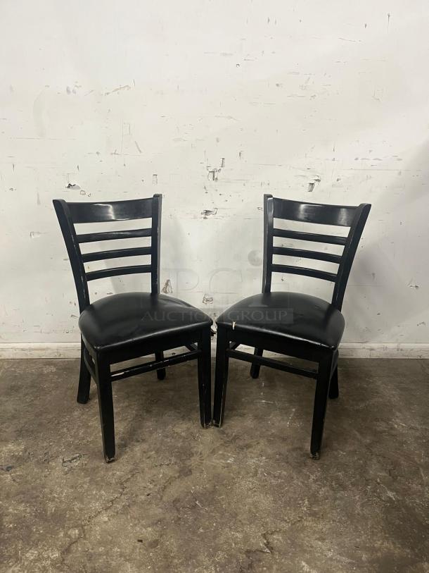 Cafe dining chairs with black frames and padded vinyl seats, showing wear on edges, suitable for restaurant use.