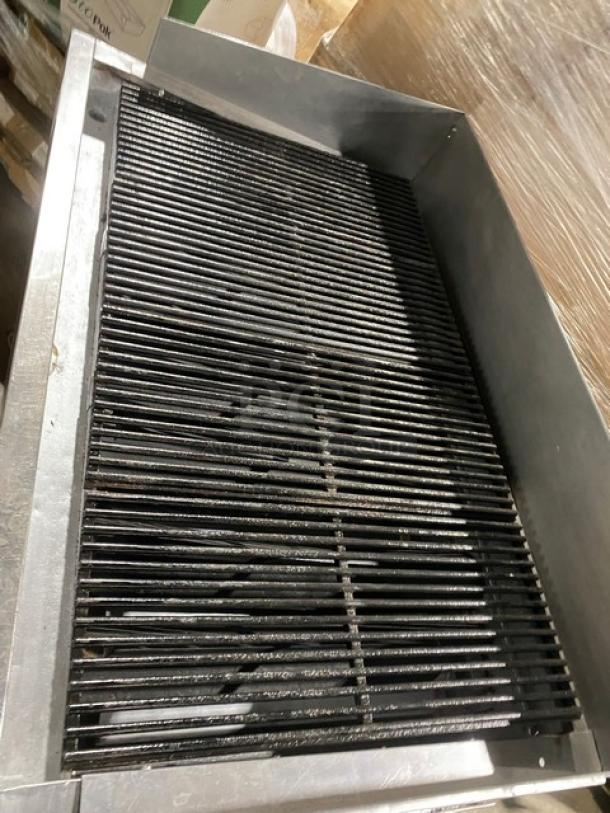 Bakers Pride stainless steel gas char broiler with radiant heating, back and side splash, single undershelf, and casters.