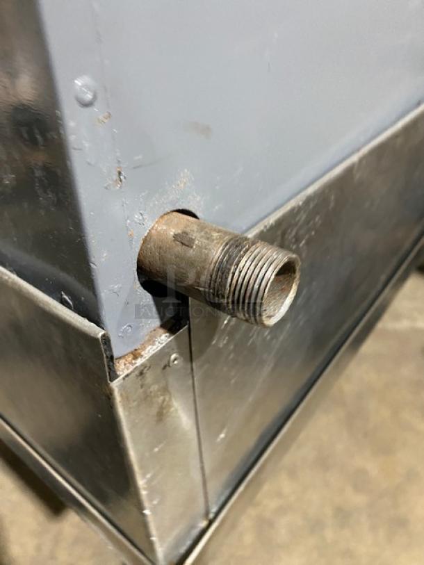 Bakers Pride stainless steel gas-powered char broiler corner detail, showing metal fitting and gray panel.