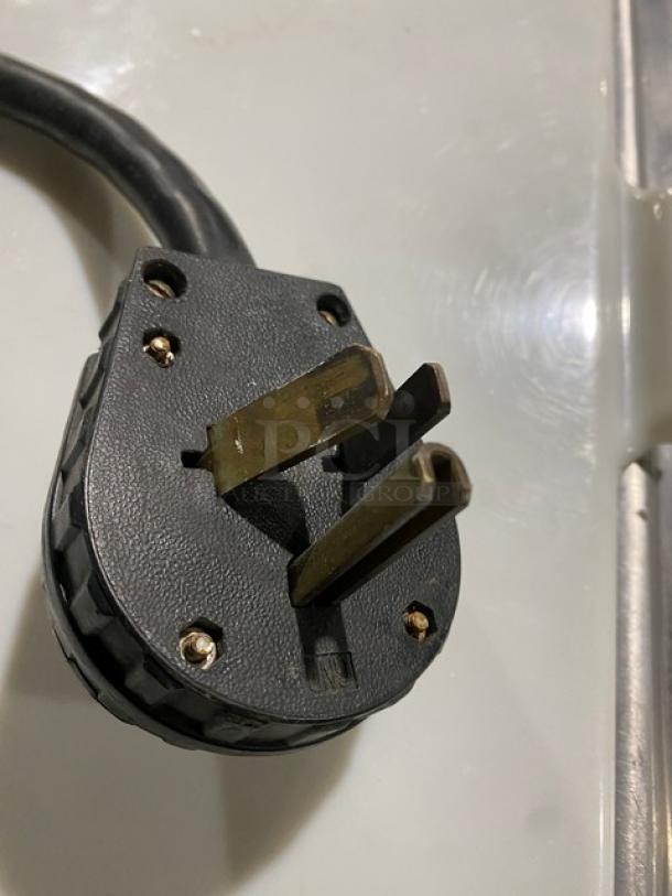 Close-up of a power plug for a Coldelite UC1131G soft serve machine, showing three-prong design and black casing.