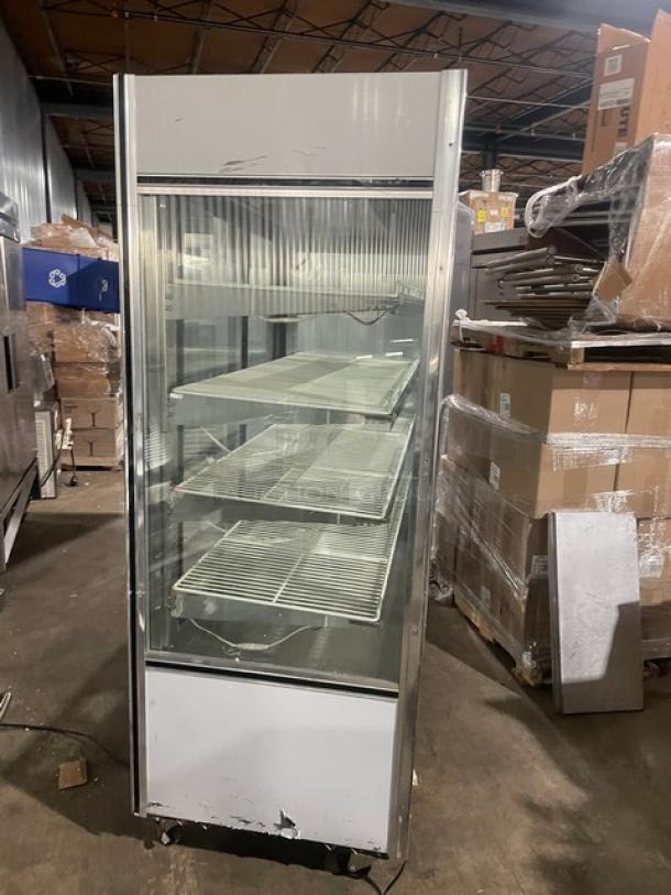 Leader stainless steel straight glass multi-tier refrigerated bakery display case with adjustable poly-coated wire racks and rear double glass sliding access door, on casters.