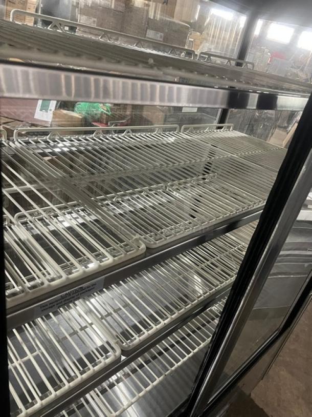 Leader commercial stainless steel refrigerated bakery display case with straight glass, adjustable poly-coated wired racks, and rear double glass sliding doors on casters.