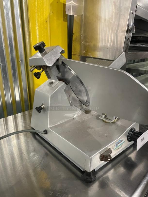 Univex commercial electric countertop meat slicer, on legs, silver finish, appears in good condition with visible Univex label.