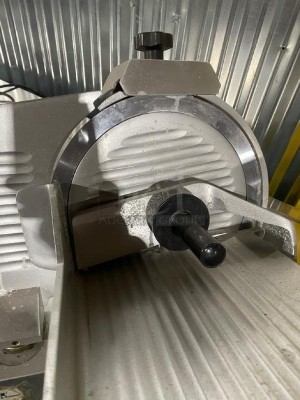 Univex commercial electric countertop meat slicer on legs, featuring durable construction with visible wear.