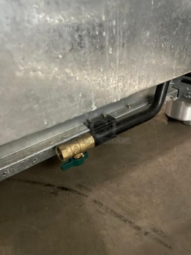 Monogram stainless steel gas-powered 6-burner range/oven combo, featuring wired oven rack, visible gas connector.