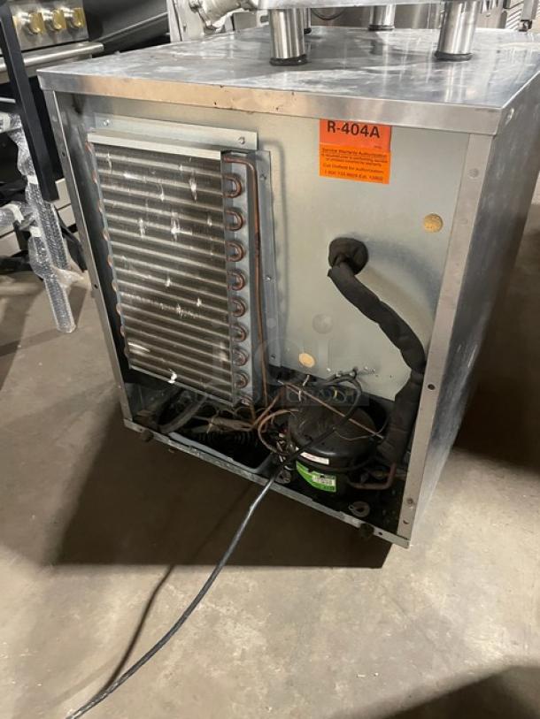 Delfield 406-STAR2 stainless steel undercounter refrigerator, exposed rear view showing coils and compressor, includes poly-coated wire rack, model label visible.