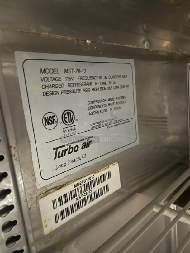 Turbo Air MST-28-12 refrigerated prep table label, indicating model, voltage (115V), and refrigerant type (R-134a). Serial number: MM2TB11010.