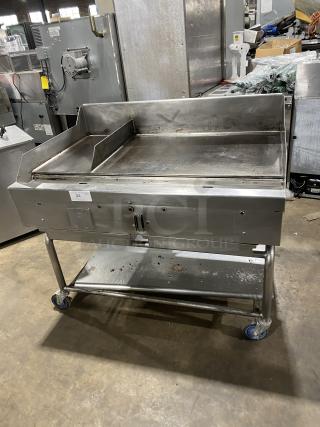 WoodStone stainless steel natural gas countertop plancha griddle with back and side splash, on welded stand with casters.
