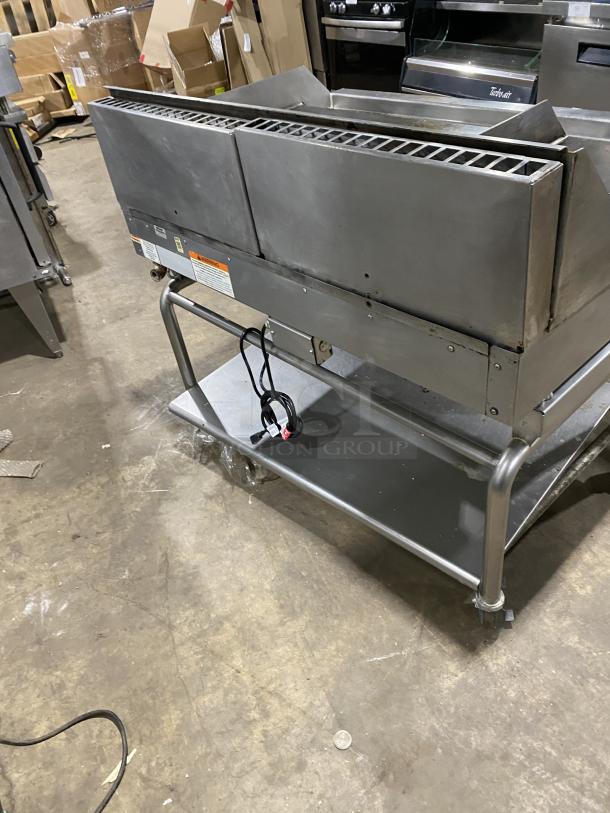 WoodStone stainless steel gas countertop plancha griddle, with back and side splash, on welded stand with casters.