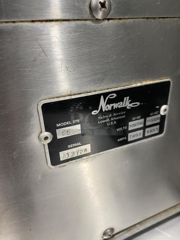 Norwalk Model 275SS stainless steel juicing machine label, showing model, serial number AI3724, voltage, and amps.