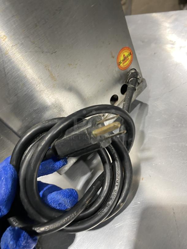 Norwalk 275SS juicing machine, stainless steel, two-stage cold press, visible power cord, fair condition, model and SN label visible.