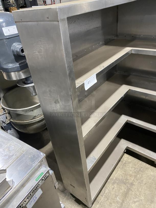 Commercial stainless steel open front cupboard unit on legs, featuring three shelves, sturdy design, and moderate wear.