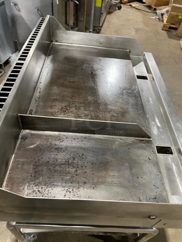WoodStone commercial stainless steel natural gas plancha griddle with back and side splash, on stand with casters.