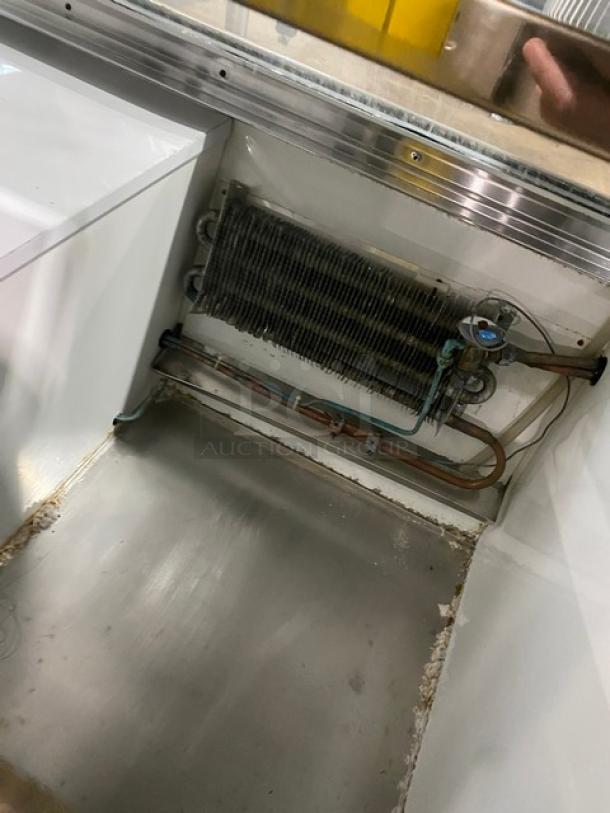 Custom Cool DEL4SC refrigerated display case interior, showing cooling coils and lower storage. Stainless steel, well-maintained.