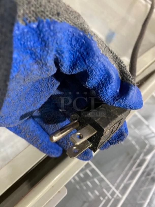 Blue-gloved hand holding a power plug of an Excelente CF289 ice cream merchandiser.