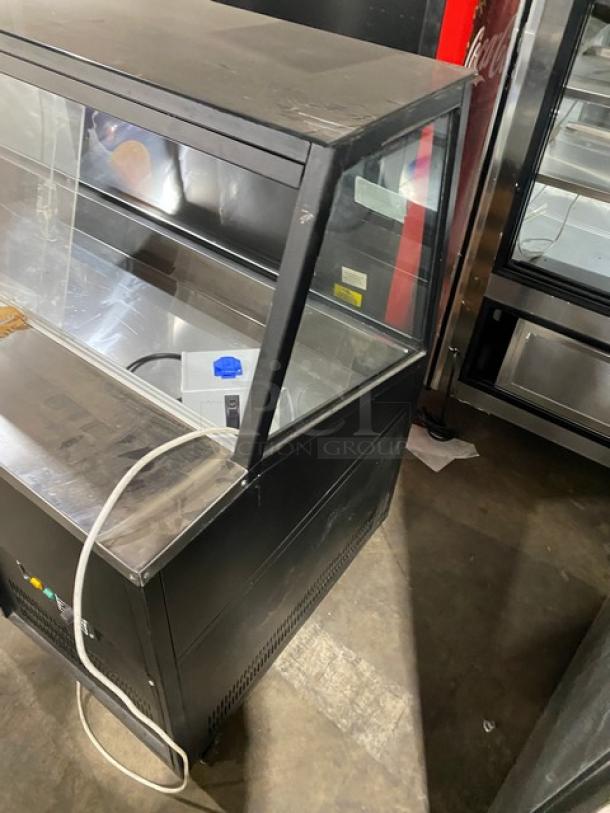 Commercial black slanted glass 60" refrigerated deli display case with wood-slat base, rear prep area, and sliding doors.